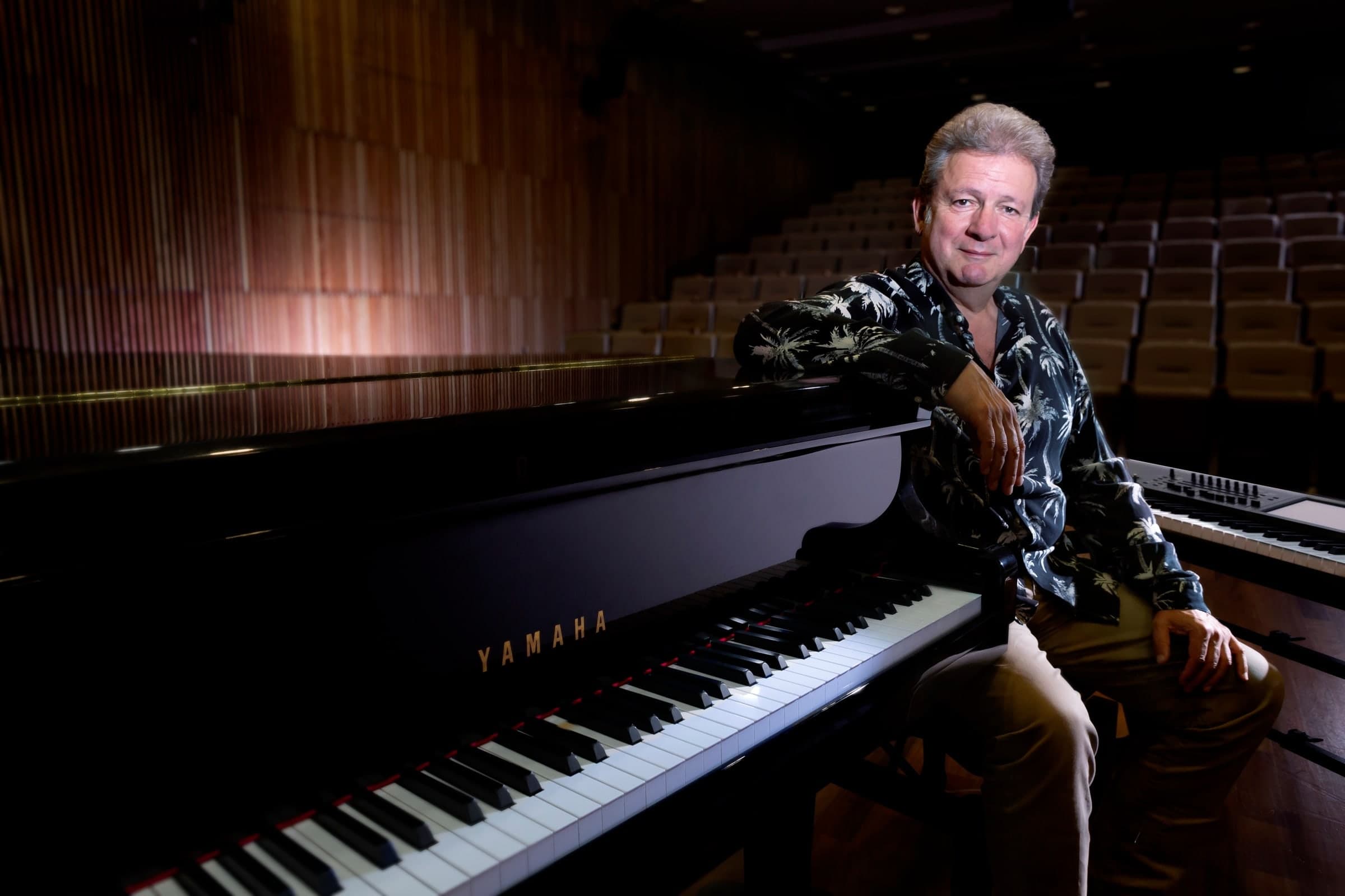 Portrait de Philippe Léogé, pianiste de jazz, assis à son piano dans une salle de concert