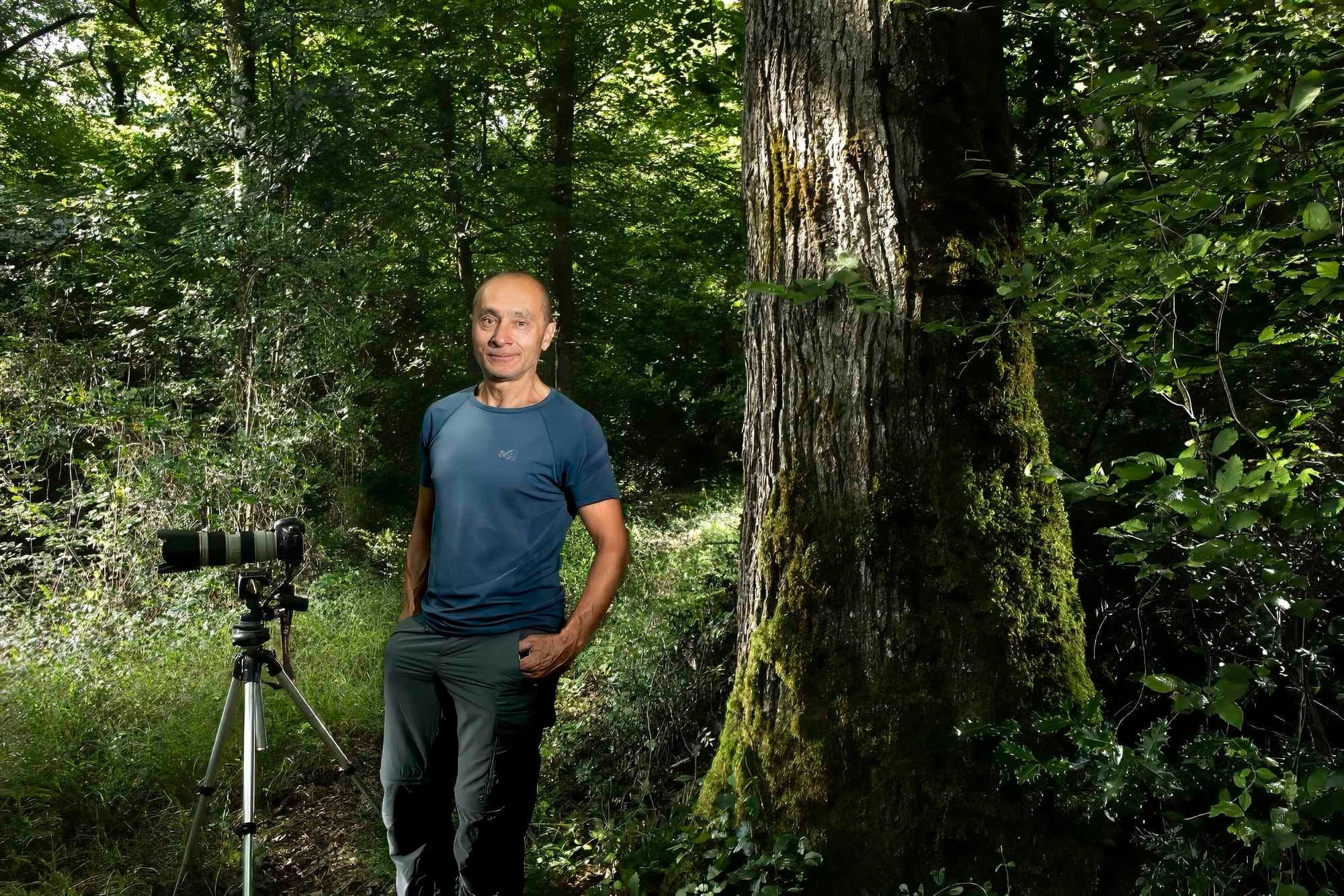 Manuel Huynh, photographe, dans une forêt avec son trépied